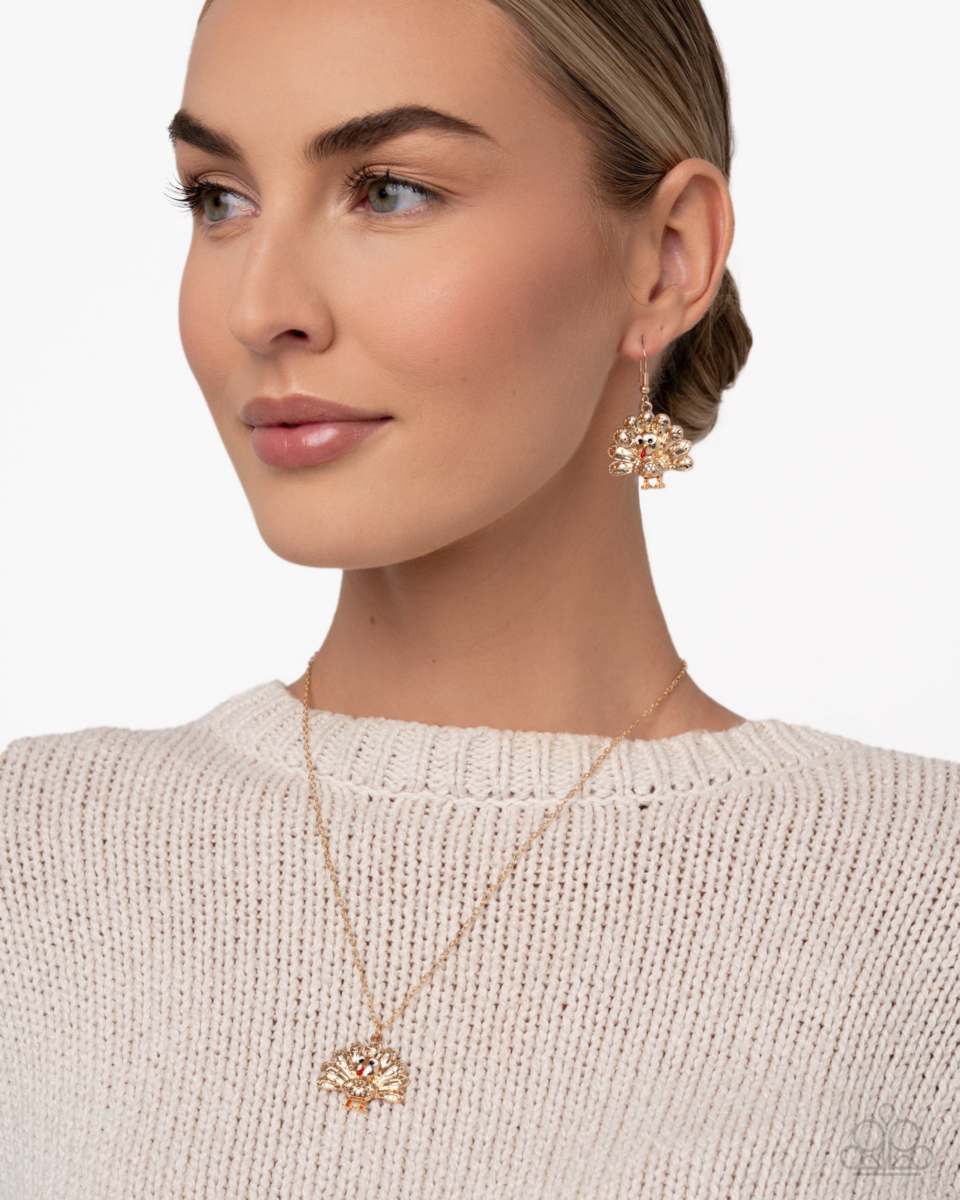 Woman wearing a gold necklace and earrings on a plain background
