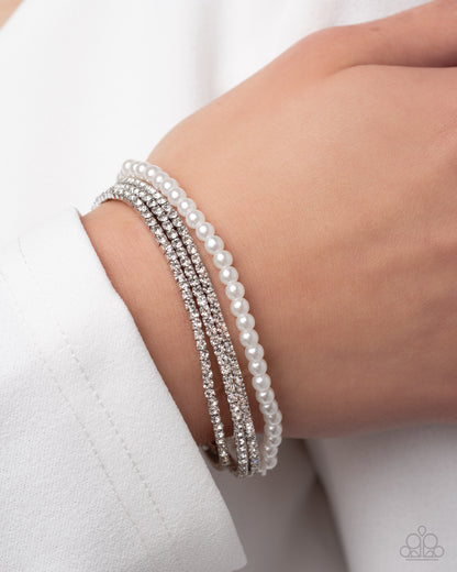 Stack of pearl bracelets on a wrist against a white background