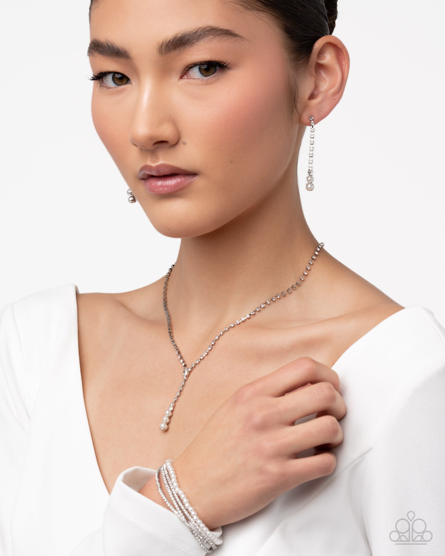 Woman wearing a silver necklace and earrings on a white background