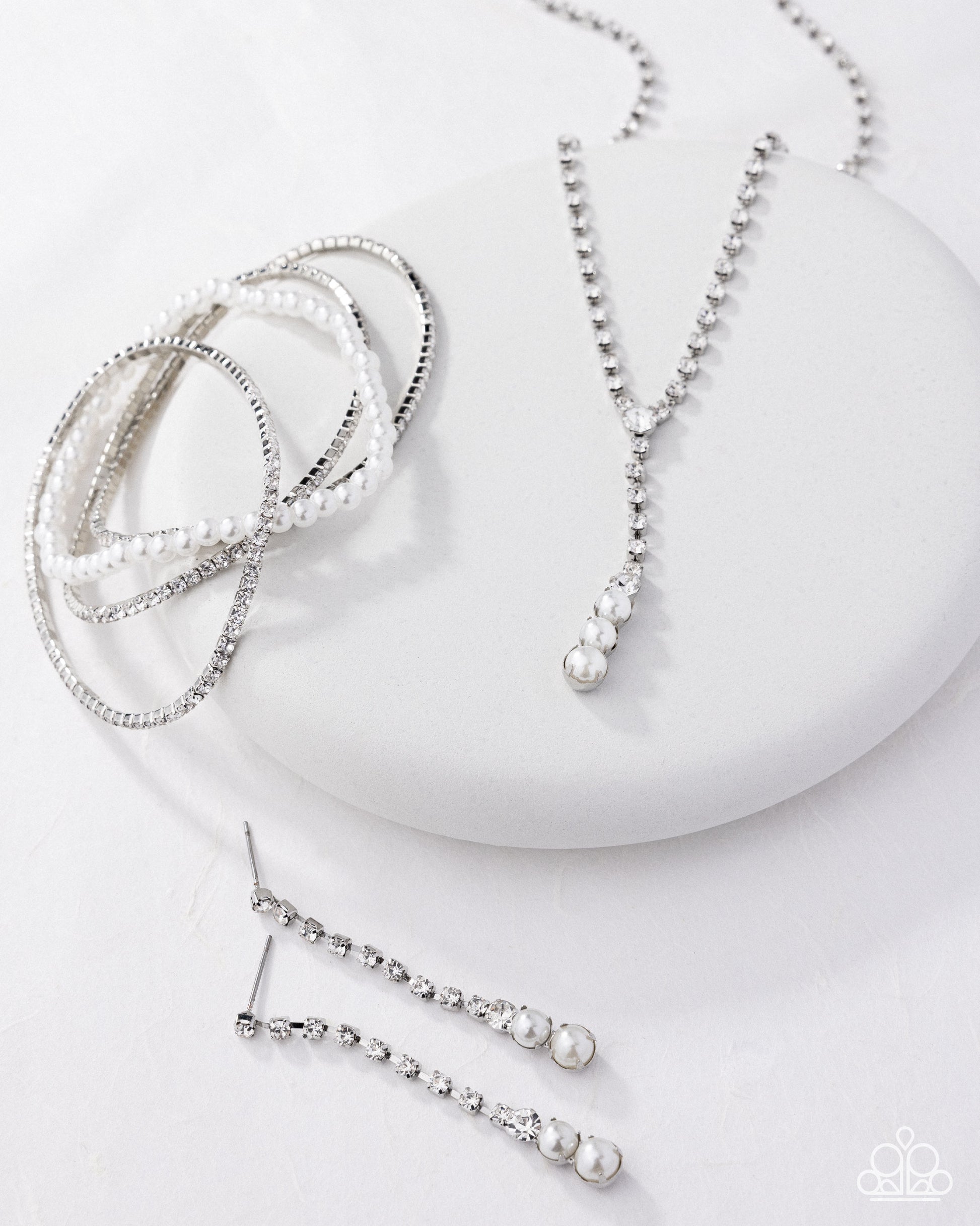 Set of pearl jewelry including a necklace, bracelet, and earring on a white surface.