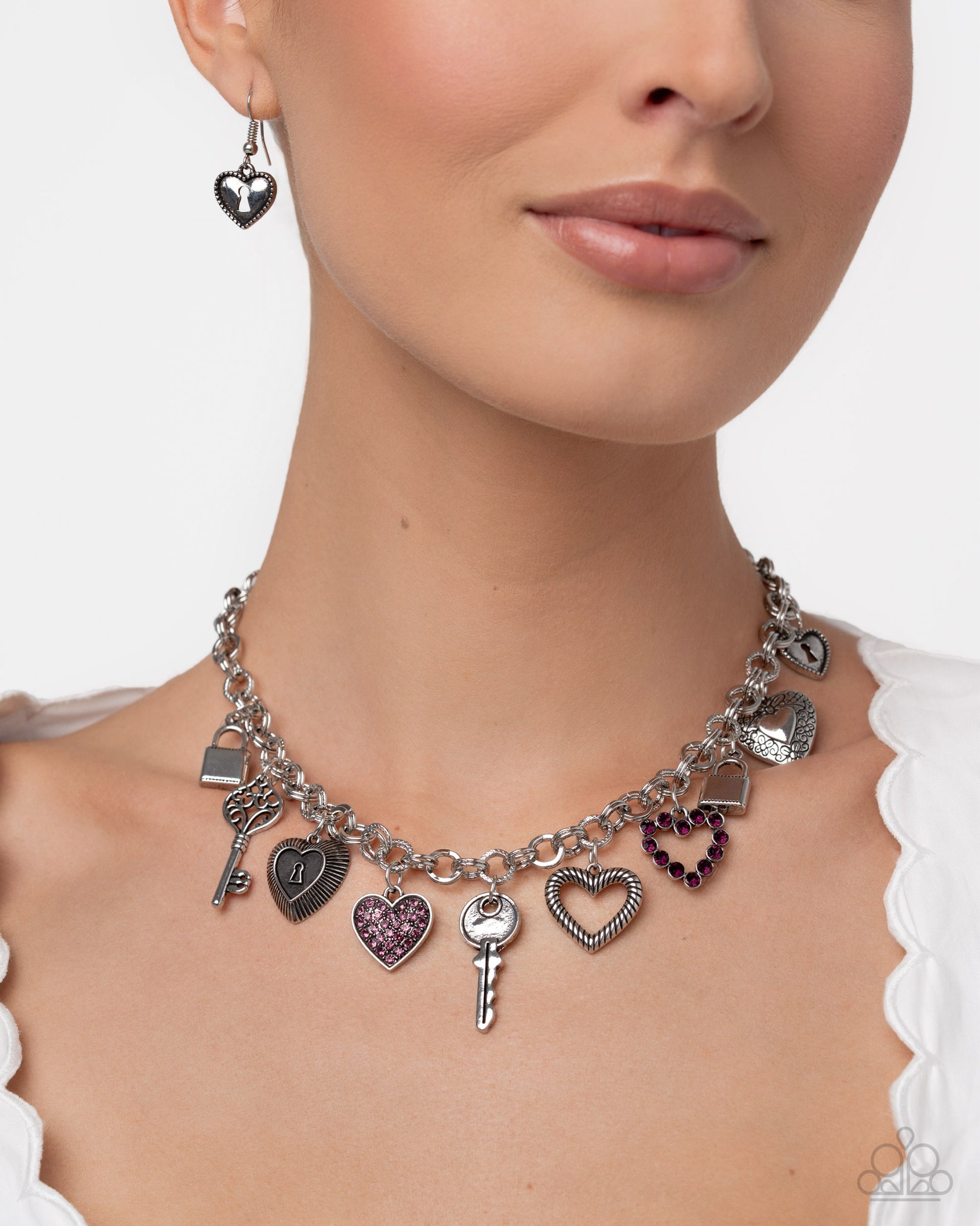 Necklace with heart and key charms worn by a model on a white background