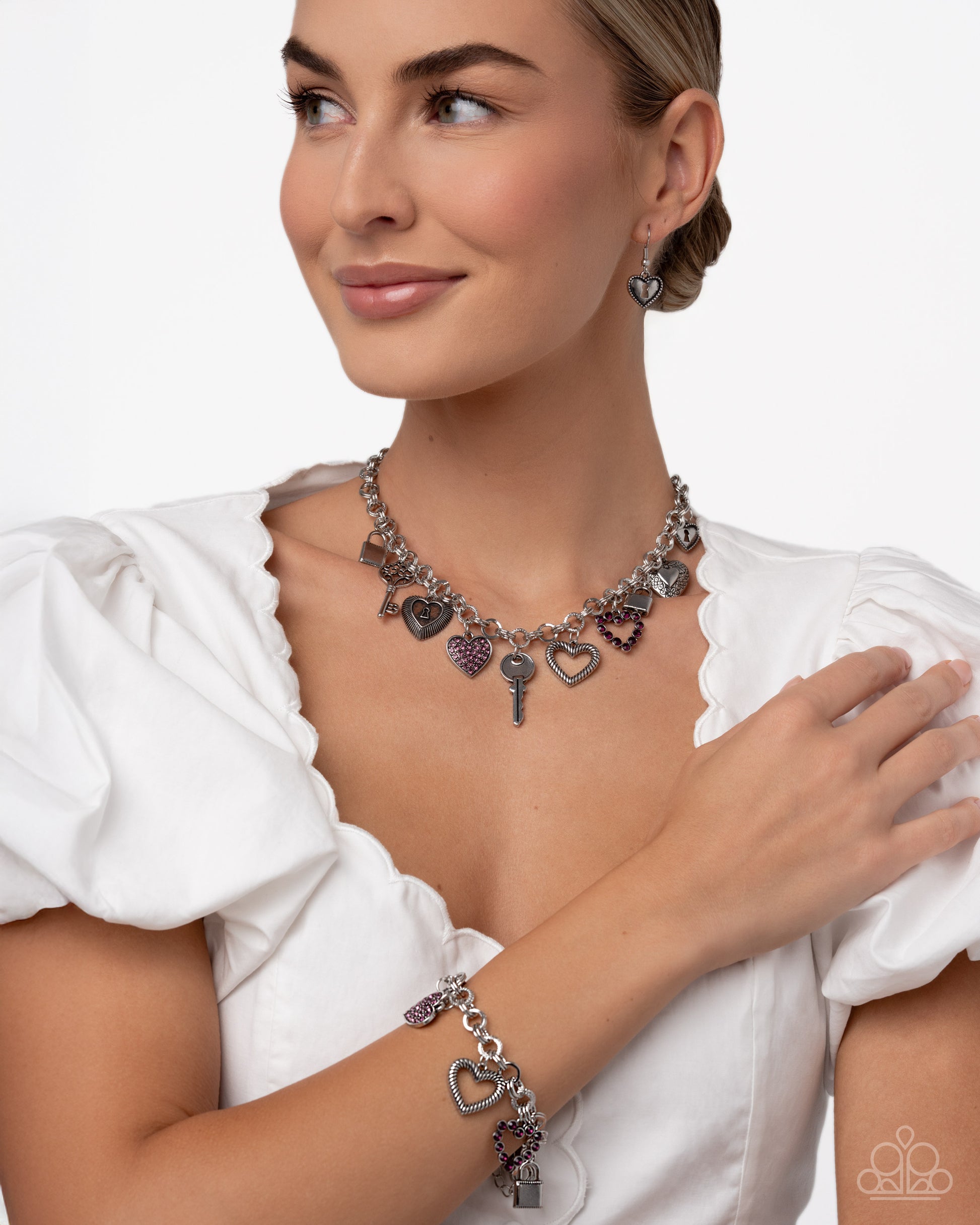 Woman wearing a silver necklace and bracelet with charms on a white background