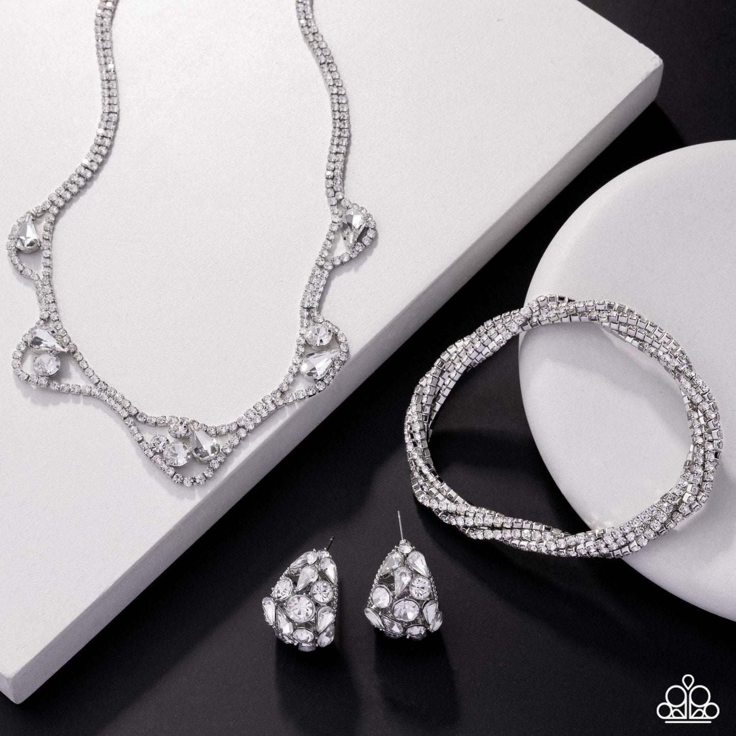 Silver jewelry set including necklace, bracelet, and earrings on a black and white background