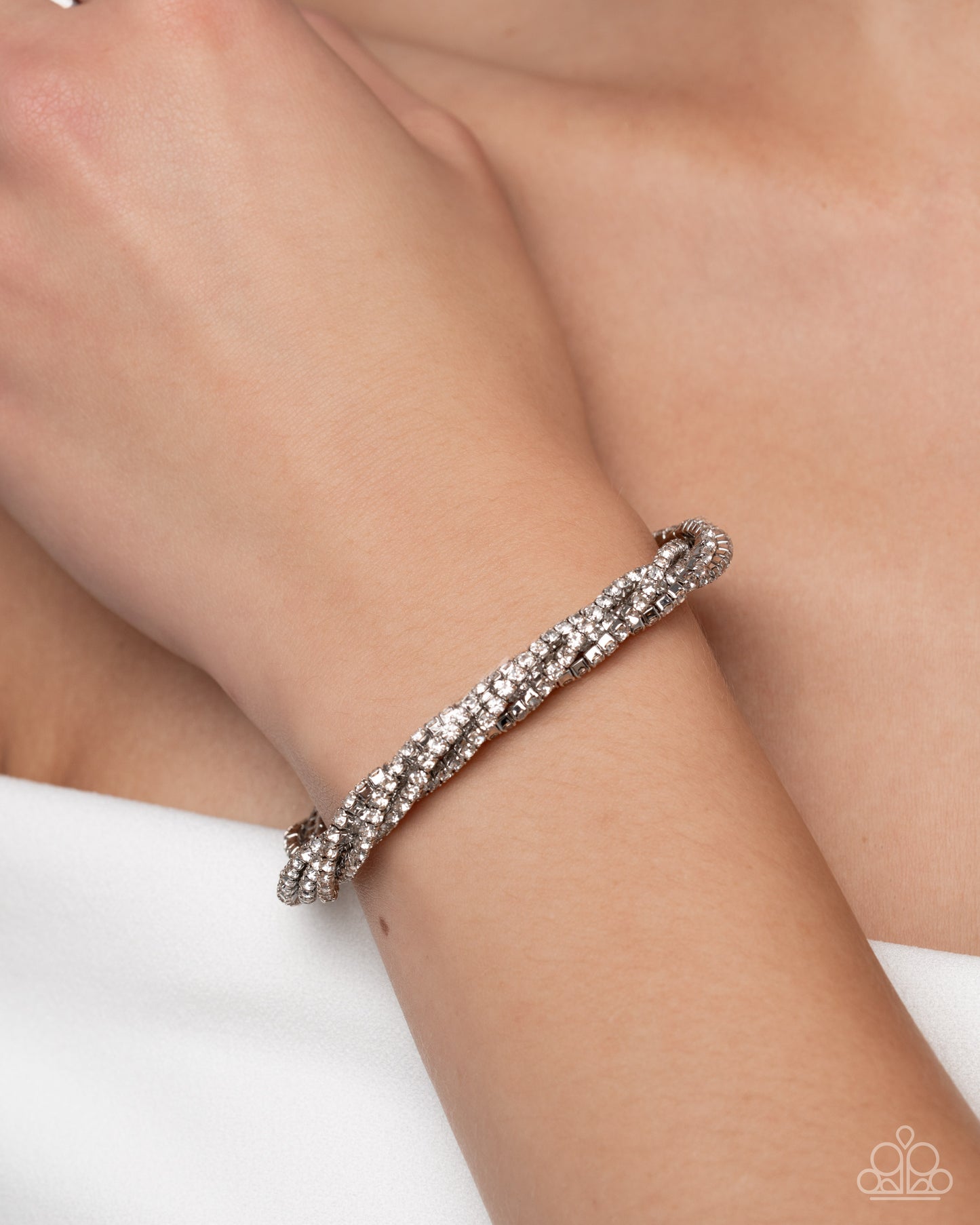 Silver bracelet on a wrist with a plain background