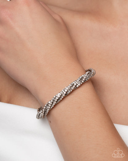 Silver bracelet on a wrist with a plain background