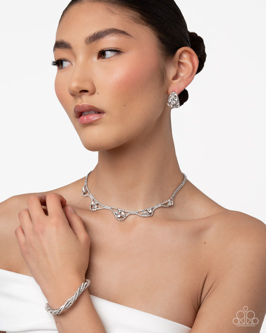 Woman wearing a silver necklace, earrings, and bracelet on a white background