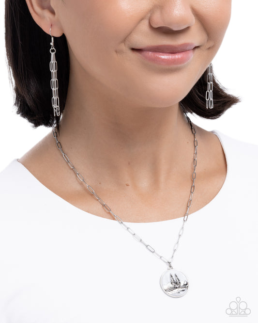 Person wearing a silver necklace and earrings on a white background