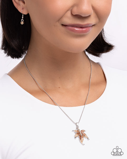 Woman wearing a silver necklace with a palm tree pendant on a white background