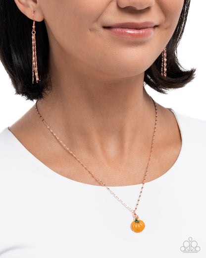 Woman wearing a rose gold necklace with a pumpkin pendant on a white background