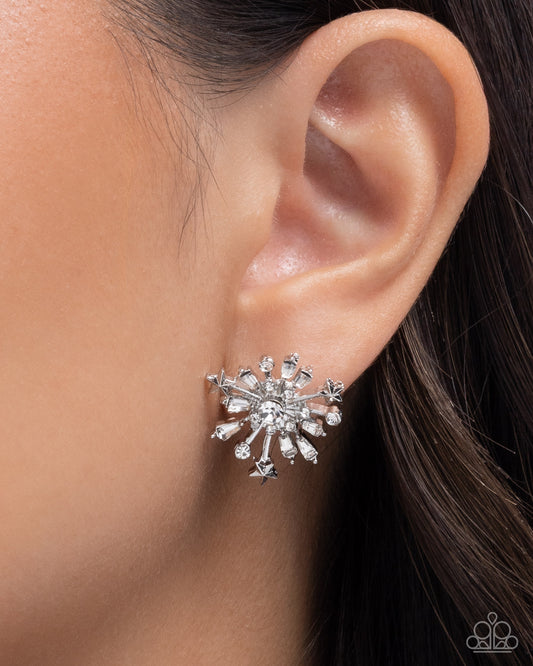 Silver star-shaped earring worn on an ear with a blurred background