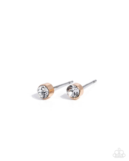 Pair of gold and clear crystal stud earrings on a white background