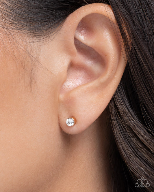 Close-up of an ear wearing a silver stud earring with a clear gemstone.
