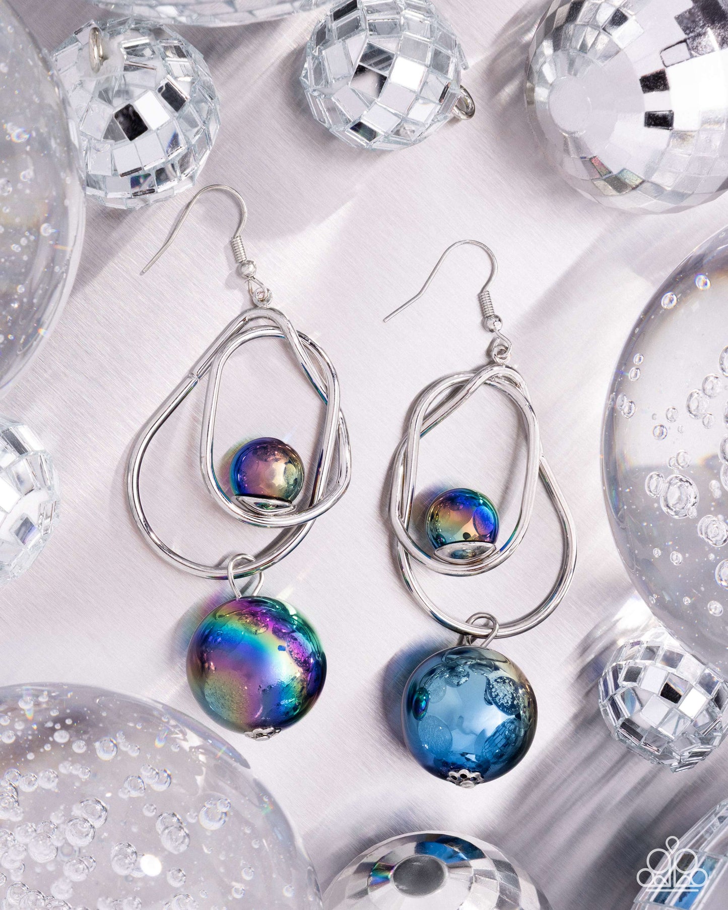 Silver earrings with colorful beads on a reflective surface