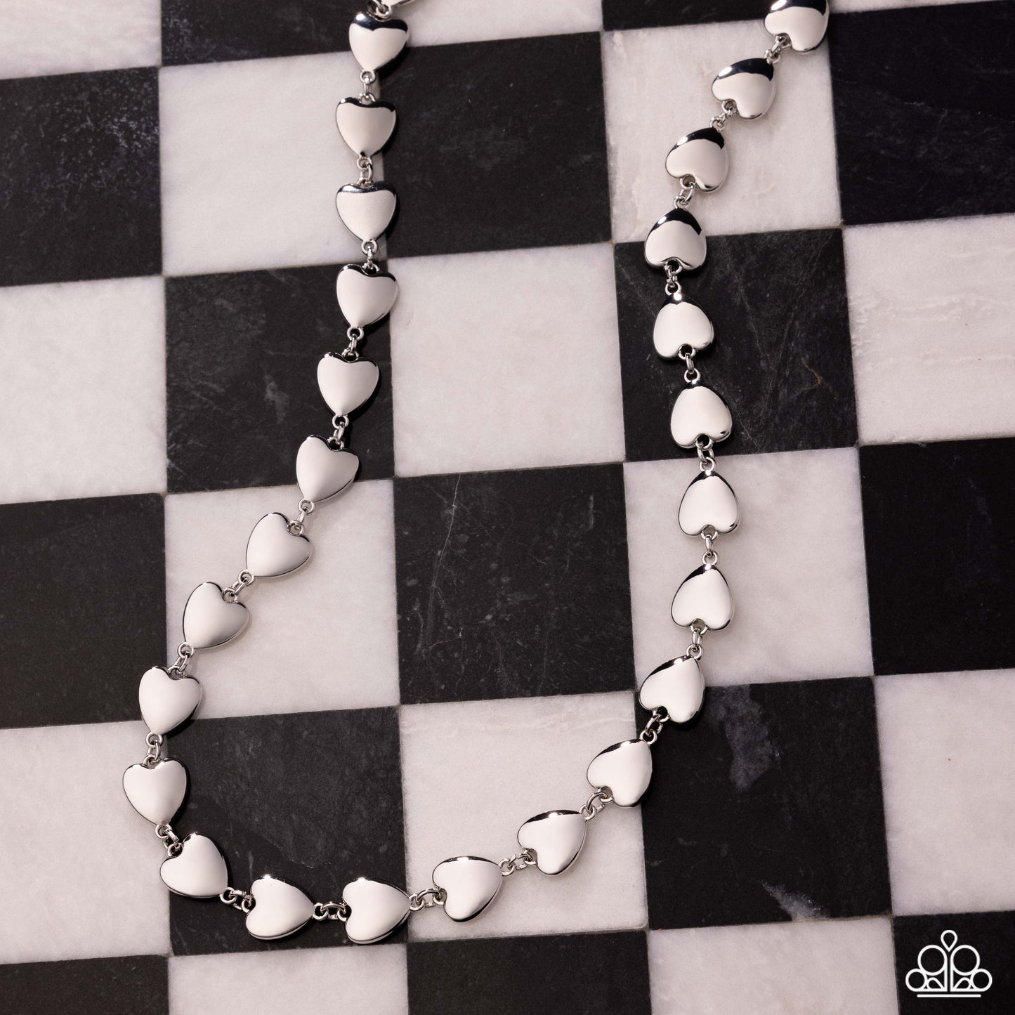 Silver heart-shaped necklace on a black and white checkered background