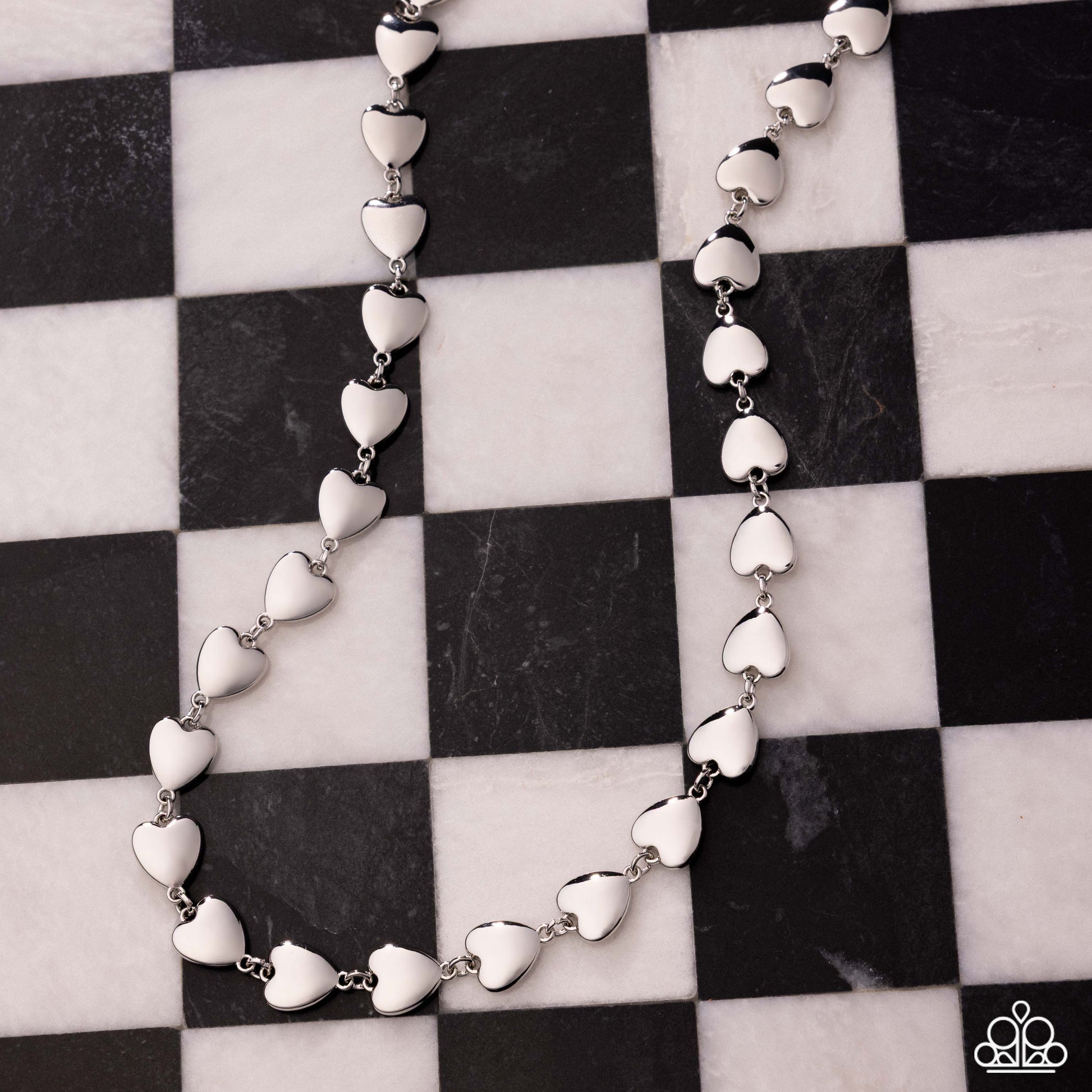 Silver heart-shaped necklace on a black and white checkered background