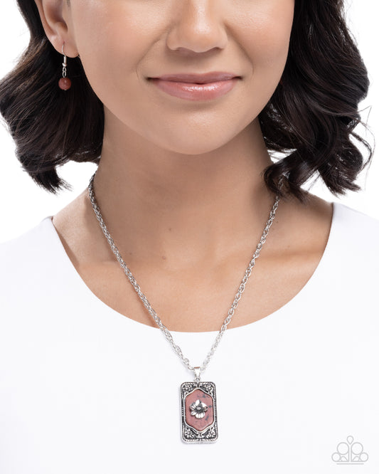 Woman wearing a silver necklace with a pink pendant on a white background