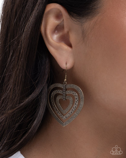Heart-shaped earrings worn by a person with dark hair.