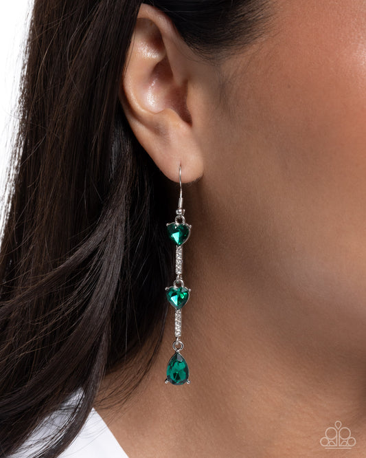 Green gemstone earring worn by a person with dark hair.