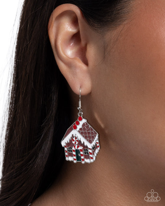 Gingerbread house earring worn by a person with dark hair.