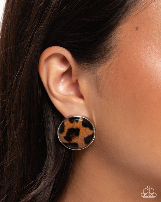 Leopard print earring worn by a person with dark hair.