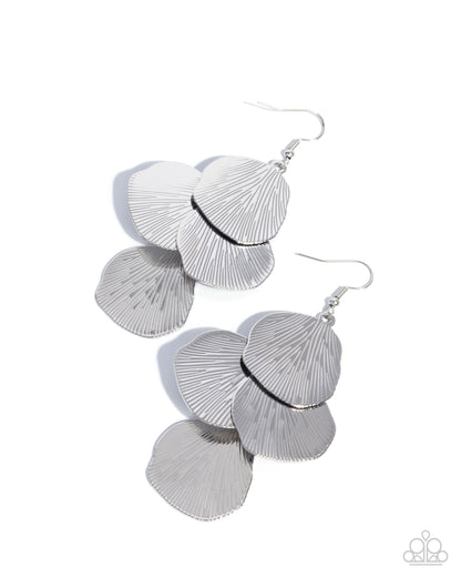 A pair of silver drop earrings with layered, fan-shaped textured metal pieces and fishhook wires, shown on a plain white background.