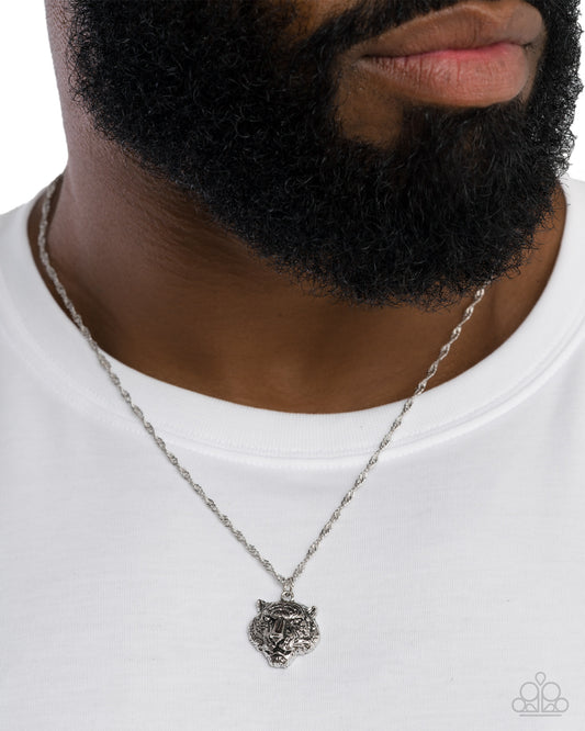 Man wearing a silver necklace with a detailed pendant on a white background