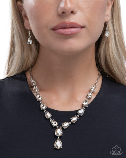 Woman wearing a silver necklace and earrings on a plain background
