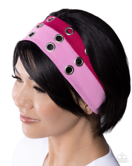 Pink headband with black grommets worn by a model on a white background