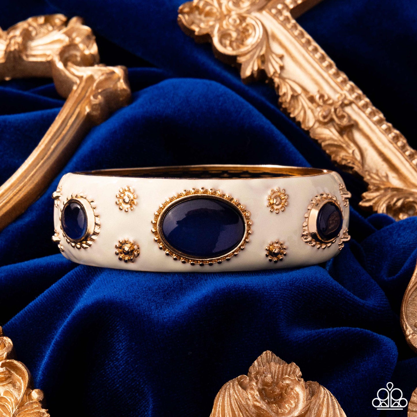 Decorative bracelet with gold accents and blue stones on a blue fabric background