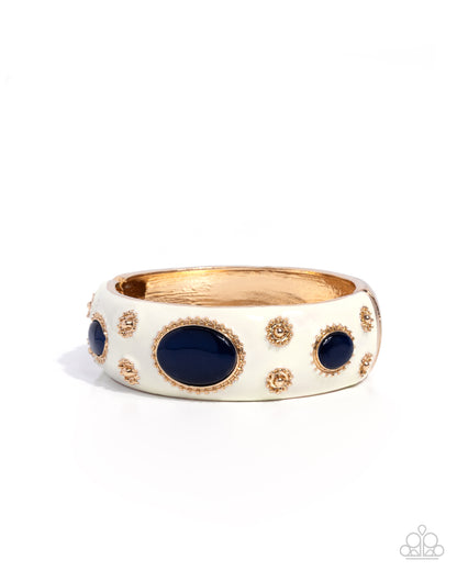Gold ring with blue stones on a white background