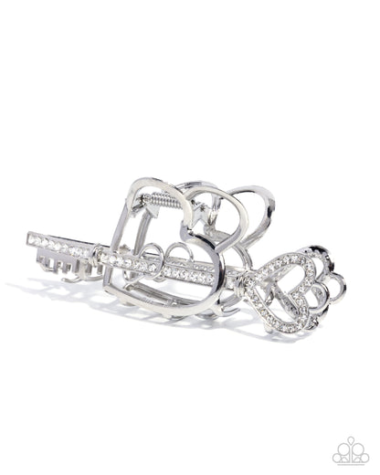 Silver hair clip with heart and bow design on a white background