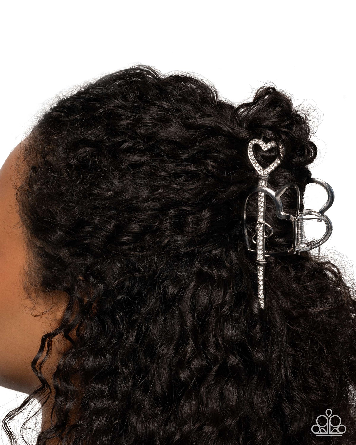 Close-up of a person with curly hair wearing a decorative hair clip on a white background