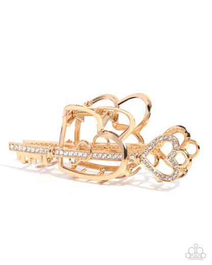 Gold key-shaped bracelet with decorative elements on a white background