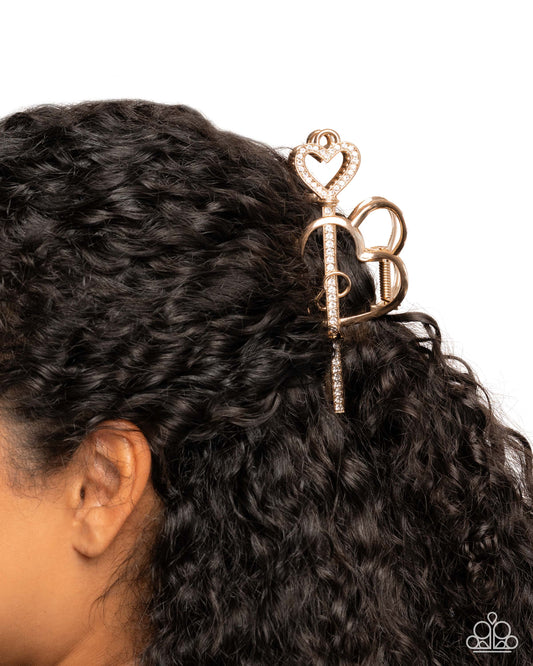 Rose gold hair accessory with heart and bow design on a person's hair against a white background