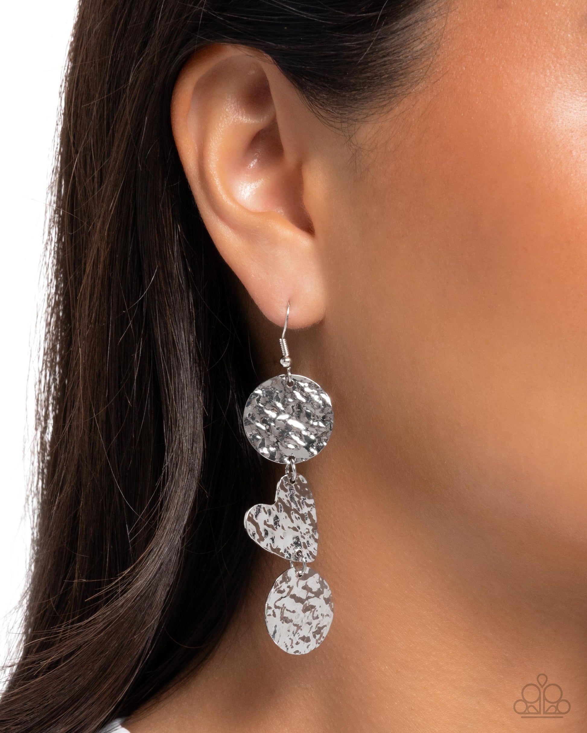 Silver earring worn by a model with dark hair and neutral background
