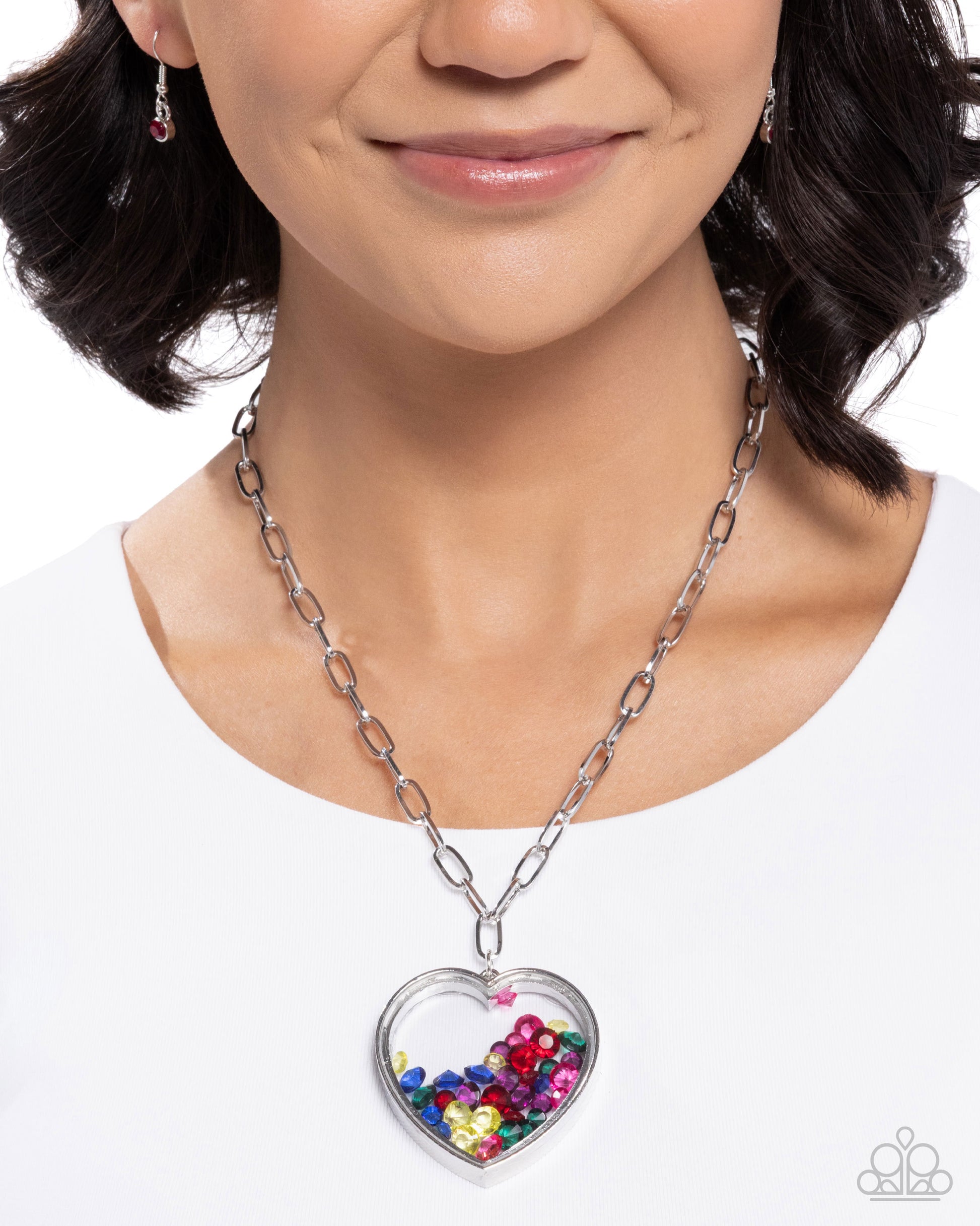 Woman wearing a silver chain necklace with a heart-shaped pendant filled with colorful beads on a white background