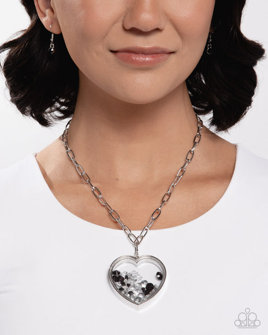 Woman wearing a silver chain necklace with a heart-shaped pendant on a white background
