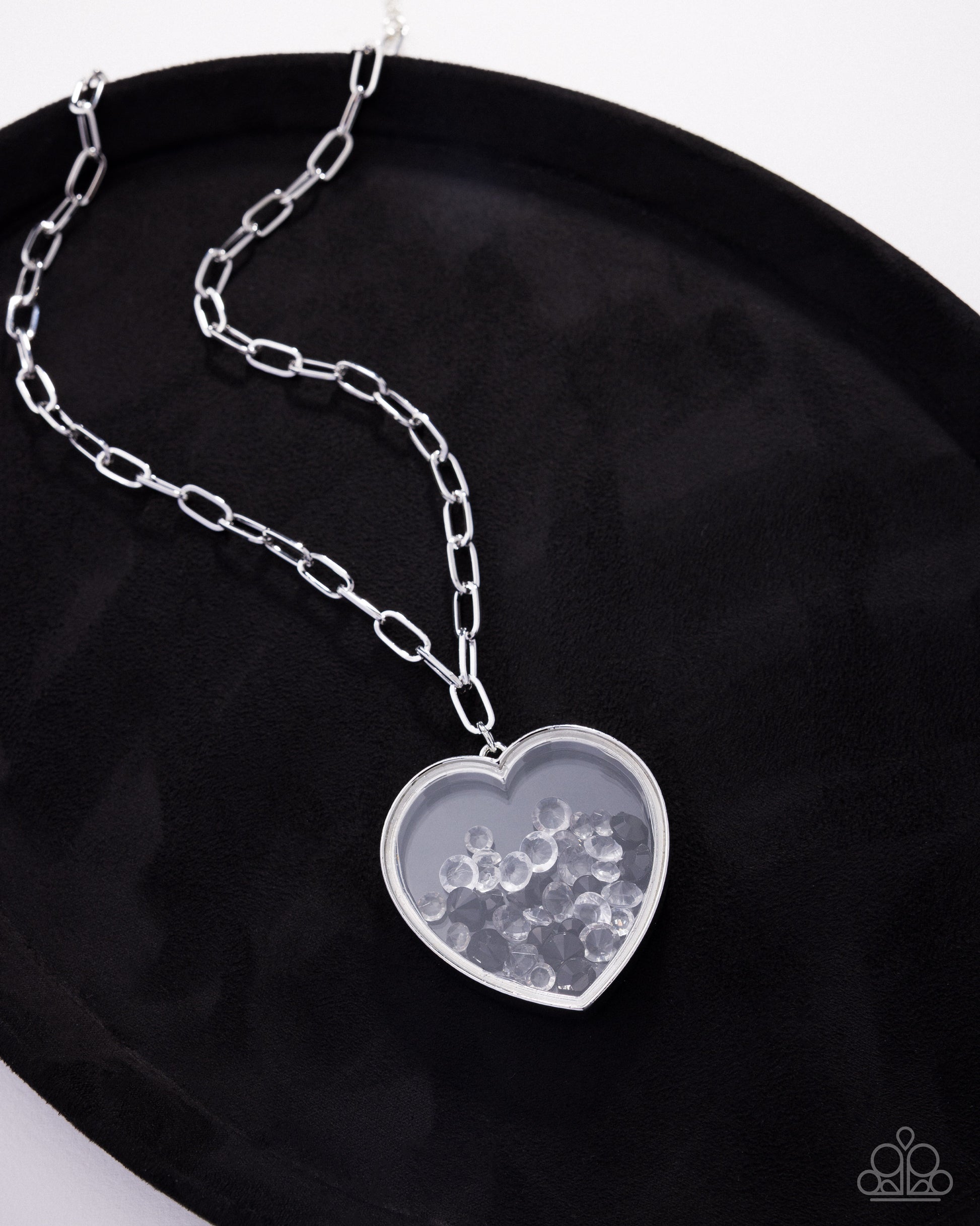 Silver chain necklace with a heart-shaped pendant on a black background