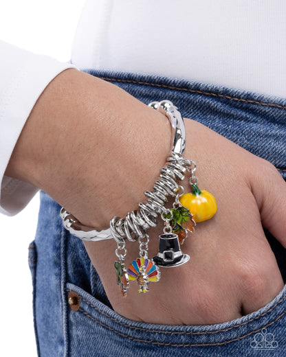 Silver bracelet with colorful charms on a wrist against a white background