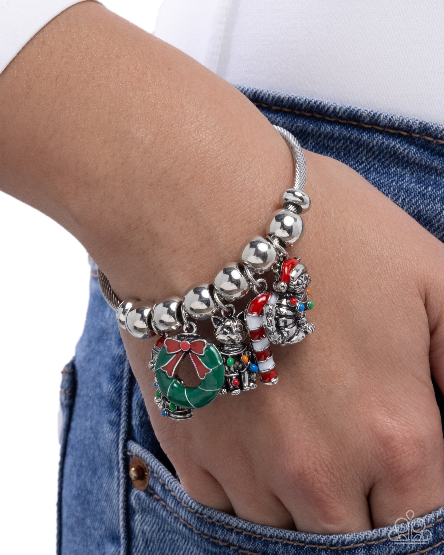 Bracelet with various charms on a wrist against a white background