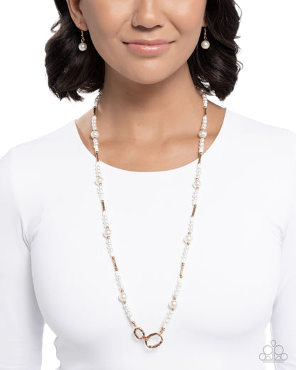 A woman wearing a long beaded necklace with white pearl-like beads, small gold-toned spacer beads, and a double-ring pendant, paired with matching drop earrings against a white background.