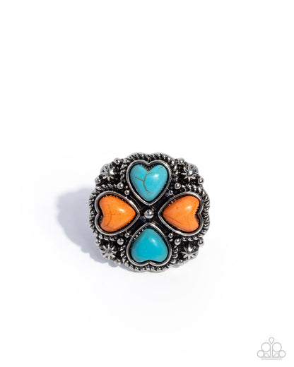 Silver ring with turquoise and orange heart-shaped stones on a white background