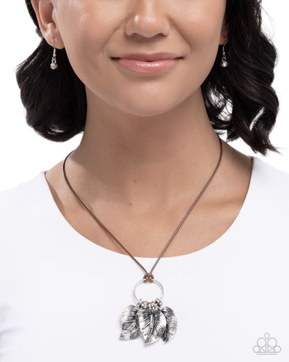 Woman wearing a silver necklace with leaf pendants on a white background