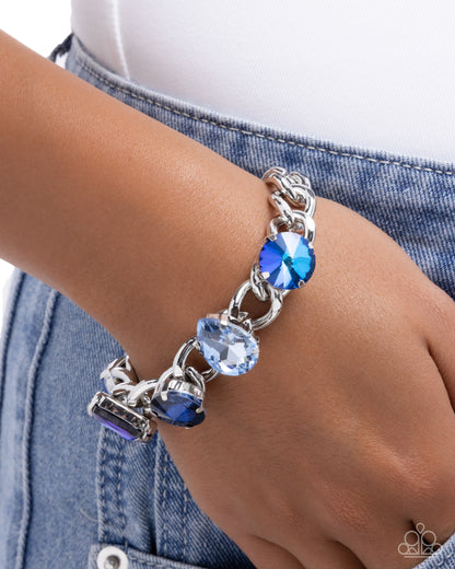 Silver bracelet with blue gemstones on a wrist against a denim background