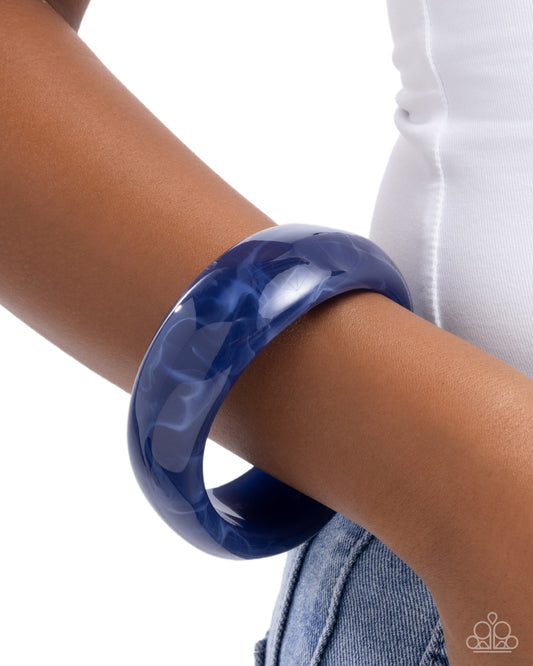 Blue bangle on a wrist with a white background