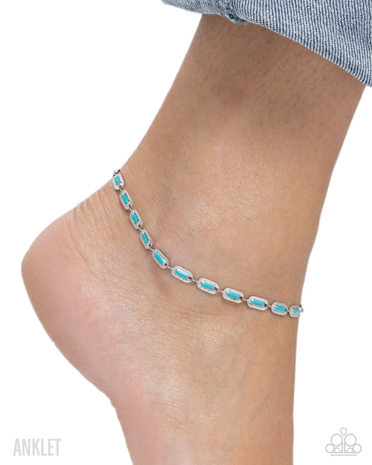 A silver anklet with a series of small rectangular turquoise-blue stones, shown worn on a person's ankle against a white background.