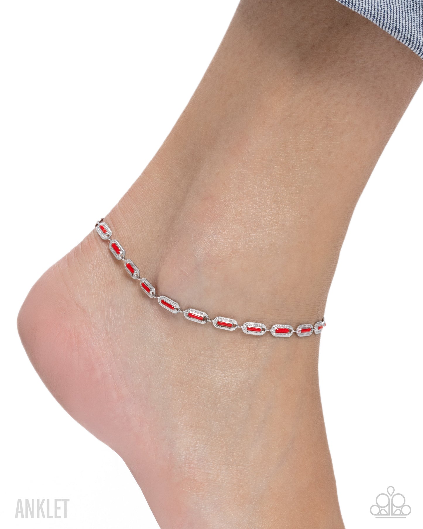 Silver anklet with red stones on a foot against a white background