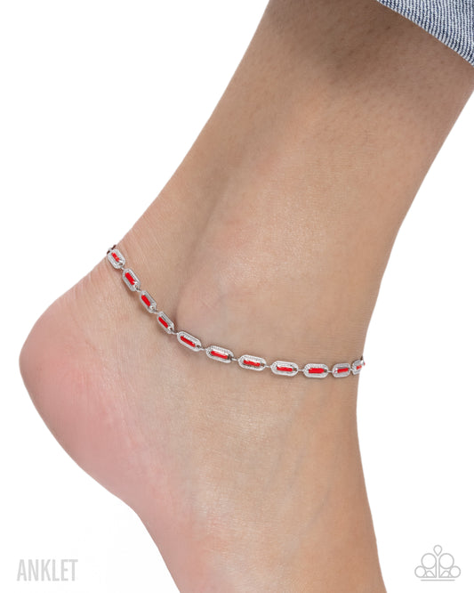 Silver anklet with red stones on a foot against a white background