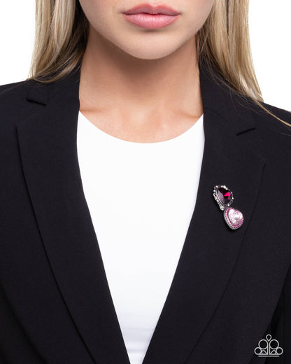 Person wearing a black blazer with a decorative brooch on a white background