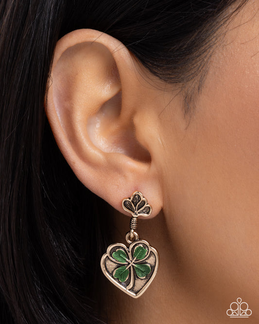 Close-up of an ear wearing a clover-shaped earring with green leaves.
